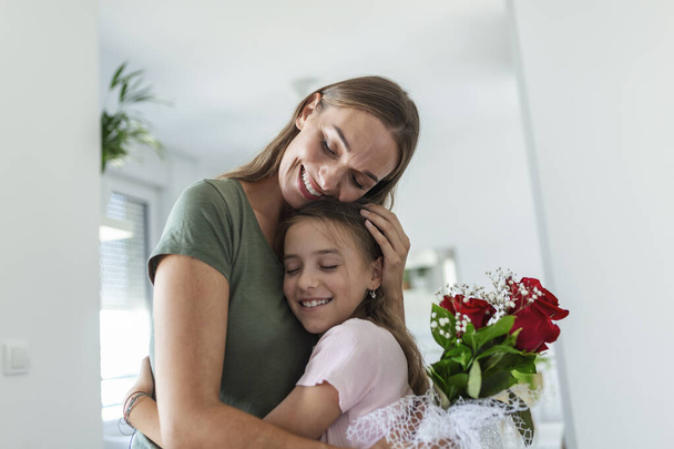 I love my you mom! Attractive young woman with little cute girl are spending time together at home, thanking for handmade card with love symbol and flowers. Happy family concept. Mother's day. - Fotó, kép