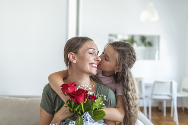 I love my you mom! Attractive young woman with little cute girl are spending time together at home, thanking for handmade card with love symbol and flowers. Happy family concept. Mother's day. - Photo, Image