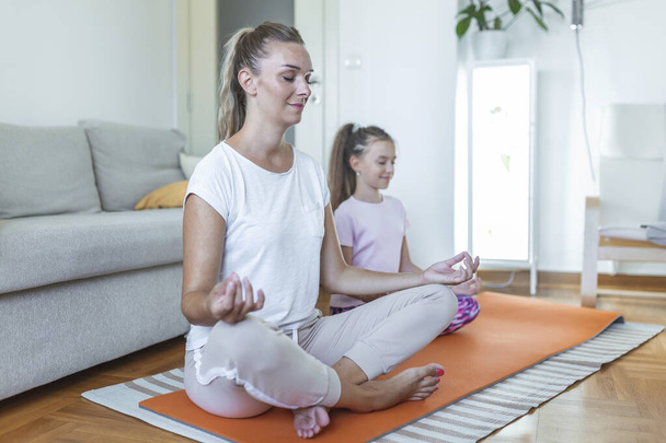 la madre di famiglia e la figlia di bambino sono impegnate in idoneità, yoga, esercizio a casa. madre e figlia che praticano yoga - Foto, immagini