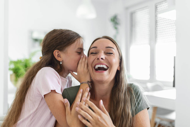 Close up image amazed mother hears incredible news from little daughter, kid girl share secret telling something interesting while mom open mouth feels surprised, trust, confidant person, fun concept - Photo, Image