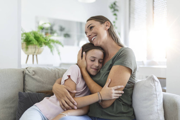 Portrait of happy young mother play hug and cuddle show love cute small preschooler daughter relaxing in living room, smiling mom and little girl child rest enjoy family weekend at home together - Photo, Image