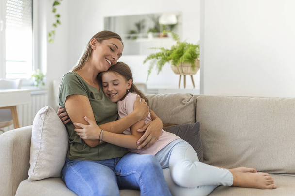 I love you so much. Portrait of happy young mother piggybacking cute smiling little daughter in living room, affectionate school age girl embracing beloved millennial female nanny or foster mom - Foto, Imagem