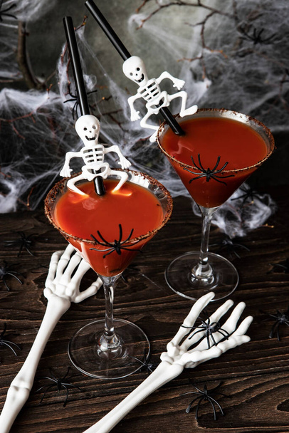 Halloween alcoholic cocktail Bloody Mary on scary dark background with bones, cob web and spiders, festive drink for party - Фото, зображення