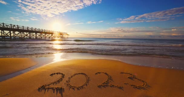 З Новим 2023 роком концепція, що витісняє на пляжі. Письмовий текст на морському пляжі на сході сонця
. - Кадри, відео