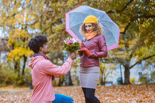 花の花束を持って秋に提案する男が、女の子は彼を拒否しています - 写真・画像