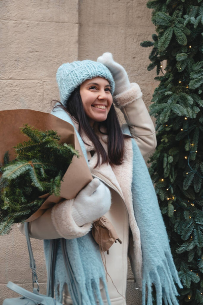 vestito invernale sorridente bella donna a piedi all'aperto tenendo bouquet albero di Natale - Foto, immagini