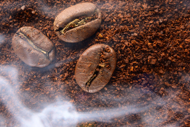 vista superior de granos de café y café molido humeante con calor, café tostado, textura de café ahumado. - Foto, imagen
