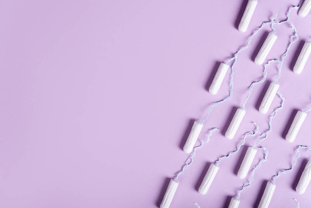 tampones de las mujeres se encuentran en una línea sobre un fondo de color lila pastel. Acostado. idea salud de la mujer, menstruación - Foto, imagen