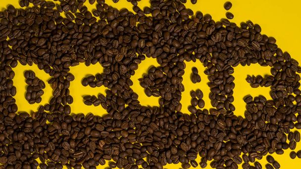 Надпись на кофейных зеренах без кофеина, вид сверху на кофе, надпись с кофе на желтом фоне. - Фото, изображение
