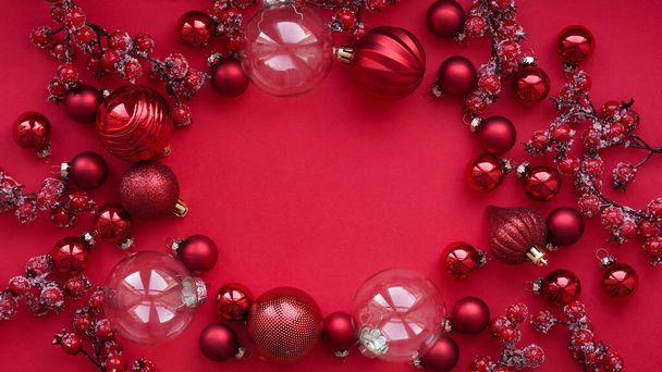 Vrolijk kerst- en nieuwjaarsbannerconcept.Close-up van veel rode kerstballen en -takken met bessen op rode achtergrond, vlakke lay, bovenaanzicht, ruimte voor tekst. Feestelijke inrichting, ansichtkaart. - Foto, afbeelding
