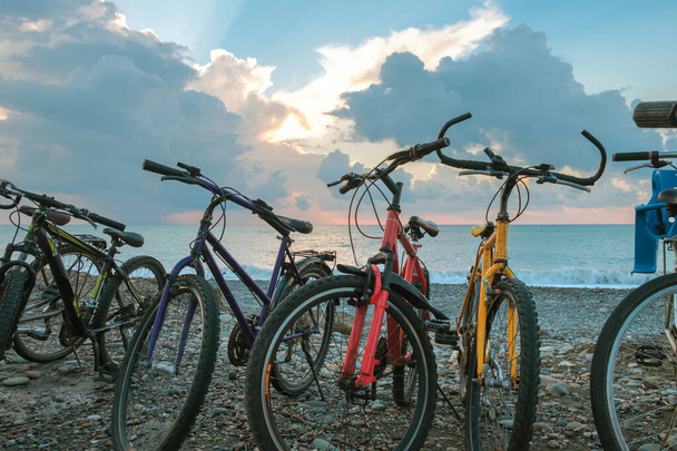 Die Reihe der Fahrräder am Strand mit blauem bewölkten Himmel und Meereshintergrund - Foto, Bild