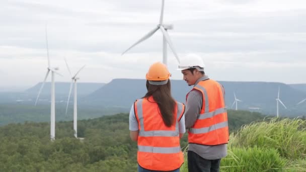 Male and female engineers working on a wind farm atop a hill or mountain in the rural. Progressive ideal for the future production of renewable, sustainable energy. - Footage, Video