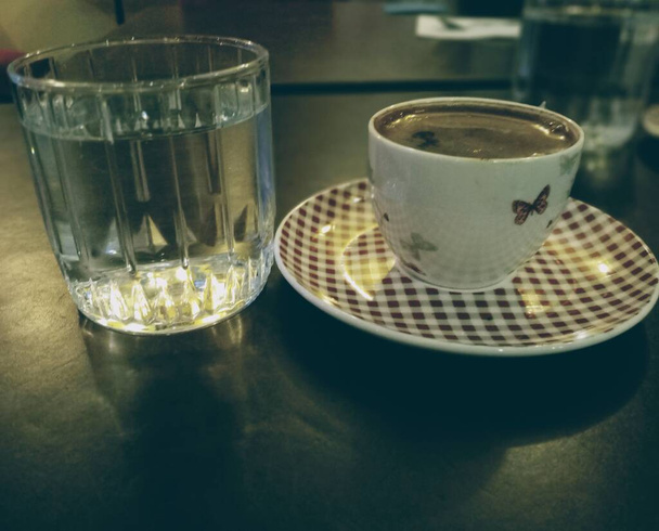 Турецкий кофе и стакан воды на столе. Традиционный кофе в Турции. - Фото, изображение