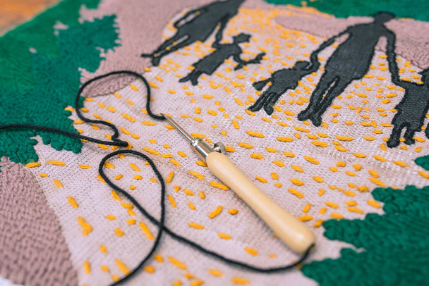Primer plano de la aguja perforadora con hilo negro en pieza de bordado abstracto de punto amarillo, germen y negro. Punch arte aguja. - Foto, imagen