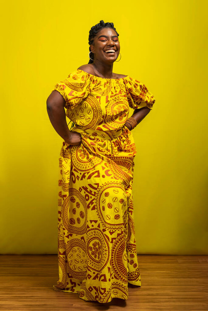Młoda afro-brazylijska kobieta uśmiechnięta na żółtym tle. Pozytywna osoba i szczęśliwa. - Zdjęcie, obraz