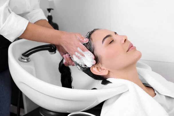Professional hairdresser washing woman's hair in beauty salon, closeup - Foto, imagen