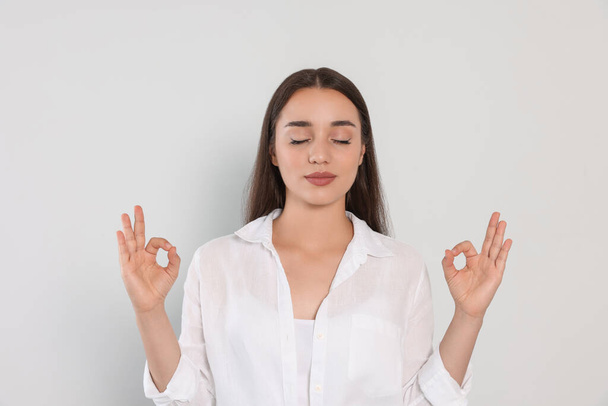 Find zen. Beautiful young woman meditating on white background - Фото, зображення
