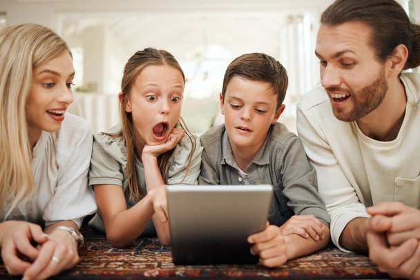 A great way to keep them entertained. a young family spending time together at home while using a digital tablet - 写真・画像