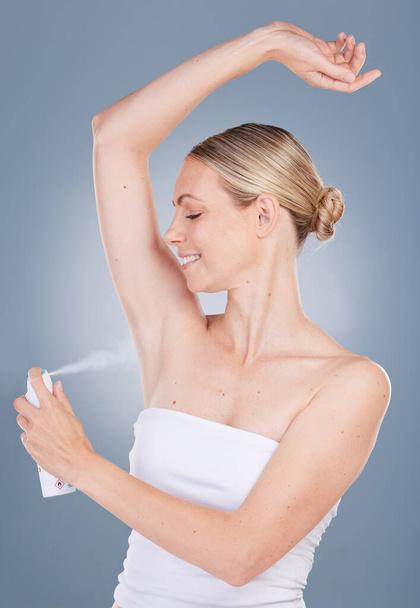Свежий и чистый. Студийный снимок привлекательной молодой женщины, использующей дезодорант на сером фоне - Фото, изображение