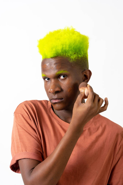 An androgynous black man posing putting on makeup, LGTBI concept, applying rouge - Photo, Image