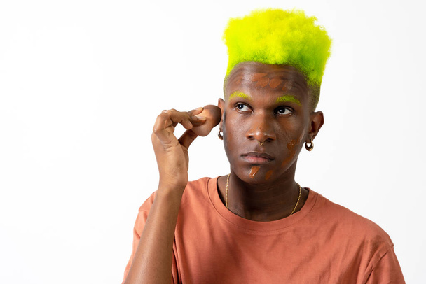An androgynous black man posing putting on makeup, LGTBI concept, applying rouge - Foto, afbeelding