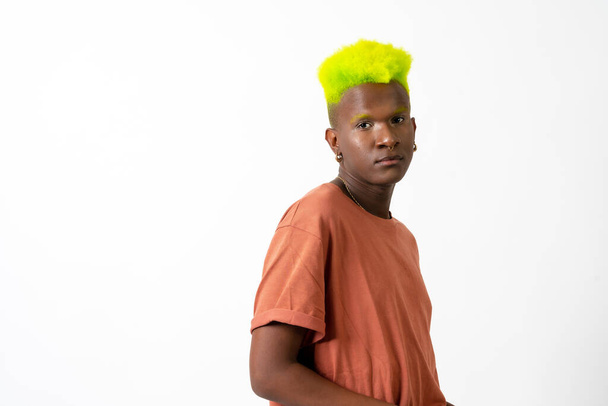 A gay black ethnicity man in studio with white background, LGTBI concept, modern green hairstyle - Foto, imagen