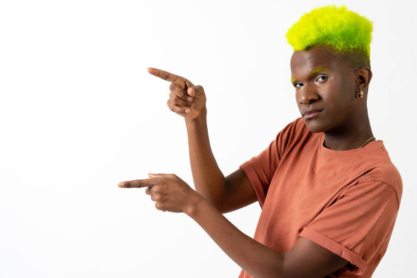 A gay black man in studio against a white background, LGTBI concept, pointing to the left - Φωτογραφία, εικόνα