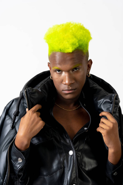 Black ethnic man in studio with white background, LGTBI concept, looking at camera with black jacket - Fotó, kép