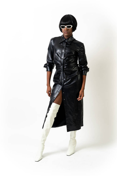 Black ethnic man in studio with white background, LGTBI concept, wearing leather skirt and sunglasses - Foto, Bild