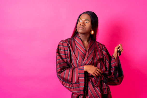 Black ethnic man in a studio, LGTBI concept, wearing a red kimono and a long wig - Foto, Imagem