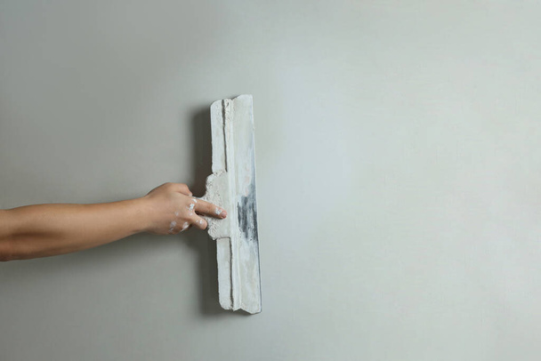 Professional worker plastering wall with putty knife, closeup - Foto, imagen