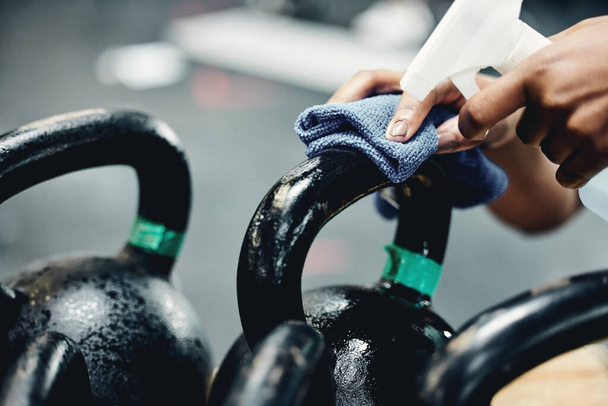 Mucha gente ha tocado esto. una mujer irreconocible desinfectando las pesas en el gimnasio antes de usarlas para su entrenamiento - Foto, imagen