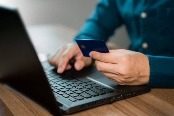 Facet używa laptopa, by zarejestrować się za pomocą karty kredytowej, by dokonywać zakupów online. Karta kredytowa bezpieczne zakupy online i koncepcja płatności. - Zdjęcie, obraz