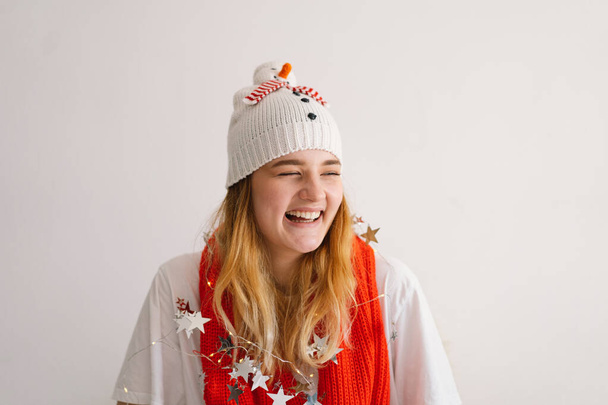 Αστείο κορίτσι με Χριστουγεννιάτικο καπέλο με χιονάνθρωπο και κόκκινο κασκόλ. Νέο Έτος και Χριστούγεννα έννοια. - Φωτογραφία, εικόνα