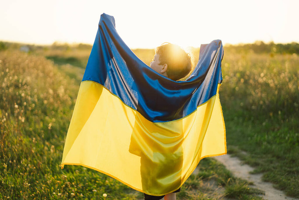 Ukrainan itsenäisyyspäivä. Lapsi poika valkoinen t-paita keltainen ja sininen lippu Ukrainan alalla. Ukrainan lippu. Perustuslakipäivä. Seistä Ukrainan ja Tallenna - Valokuva, kuva