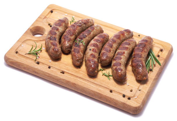 Grilled sausages on wooden cutting board isolated on white background. - Фото, зображення