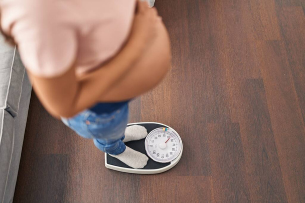 Jeune femme latine enceinte mesurant le poids à la maison - Photo, image