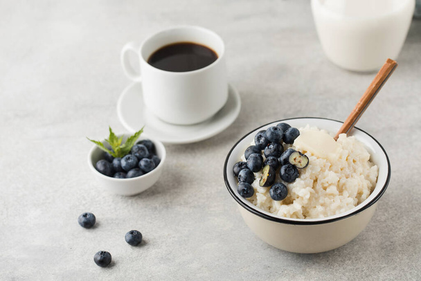 Rice milk porridge with blueberries and a mug of black coffee. The concept of a healthy and tasty breakfast. - Valokuva, kuva