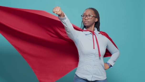 Portrait of superhero with flying red cape on camera, posing as action cartoon character with costume and cloak. Showing motivation and strength in studio, positive and powerful. - Felvétel, videó