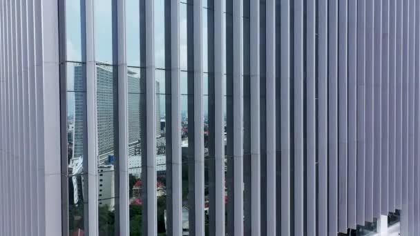 Pohybuje se k mrakům podél oken kancelářské budovy a vysokohorského moderního mrakodrapu. Mraky a obloha se odrážejí ve skle oken prázdných nemovitostí. - Záběry, video