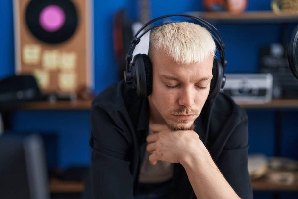 Young caucasian man artist listenint to music at music studio - Foto, Imagen