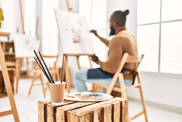 Молодий афроамериканець на задньому плані малює на художній студії.. - Фото, зображення