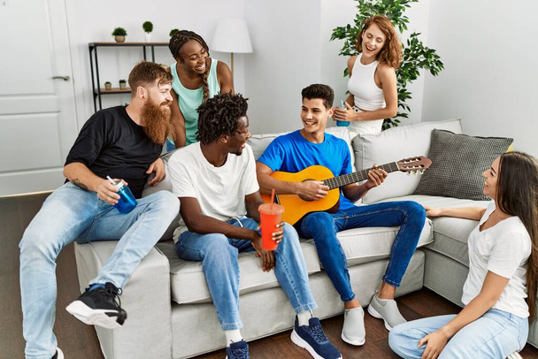 Group of young friends smiling happy and playing classical guitar at home. - Photo, Image