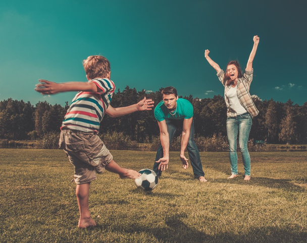 Family playing football outdoors - 写真・画像