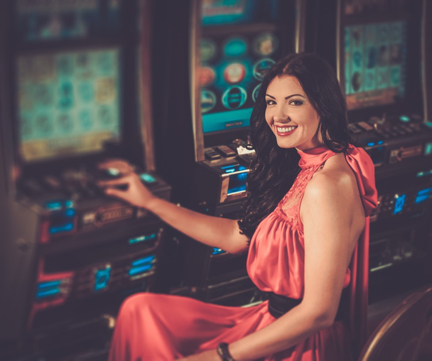Жінка в червоній сукні грає в ігровий автомат
 - Фото, зображення