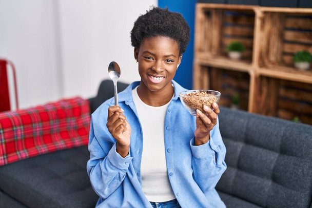 African american woman eating healthy whole grain cereals smiling with a happy and cool smile on face. showing teeth.  - Photo, Image