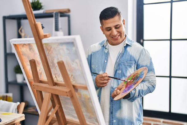 Jeune homme latin artiste souriant dessin confiant à l'atelier d'art - Photo, image