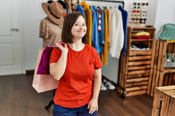 Brunette woman with down syndrome holding shopping bags at retail shop - Foto, Bild