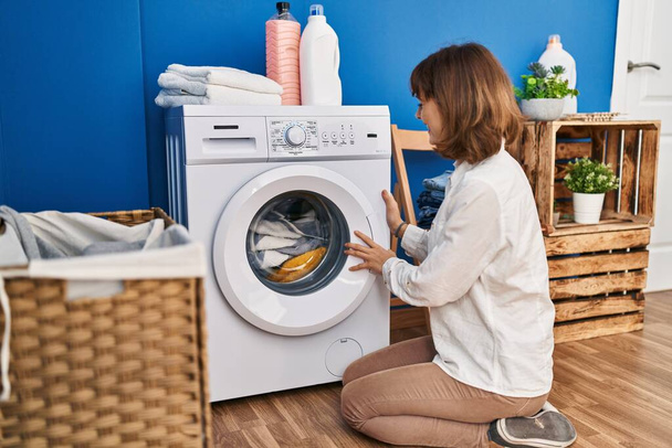 若い白人女性洗濯室で床に座って服を洗う - 写真・画像