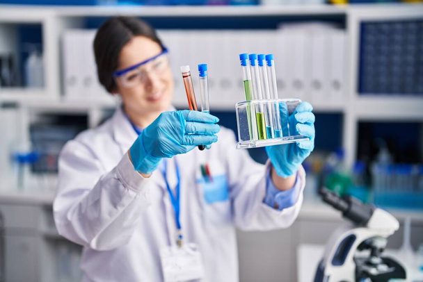 Jeune femme scientifique tenant des éprouvettes en laboratoire - Photo, image